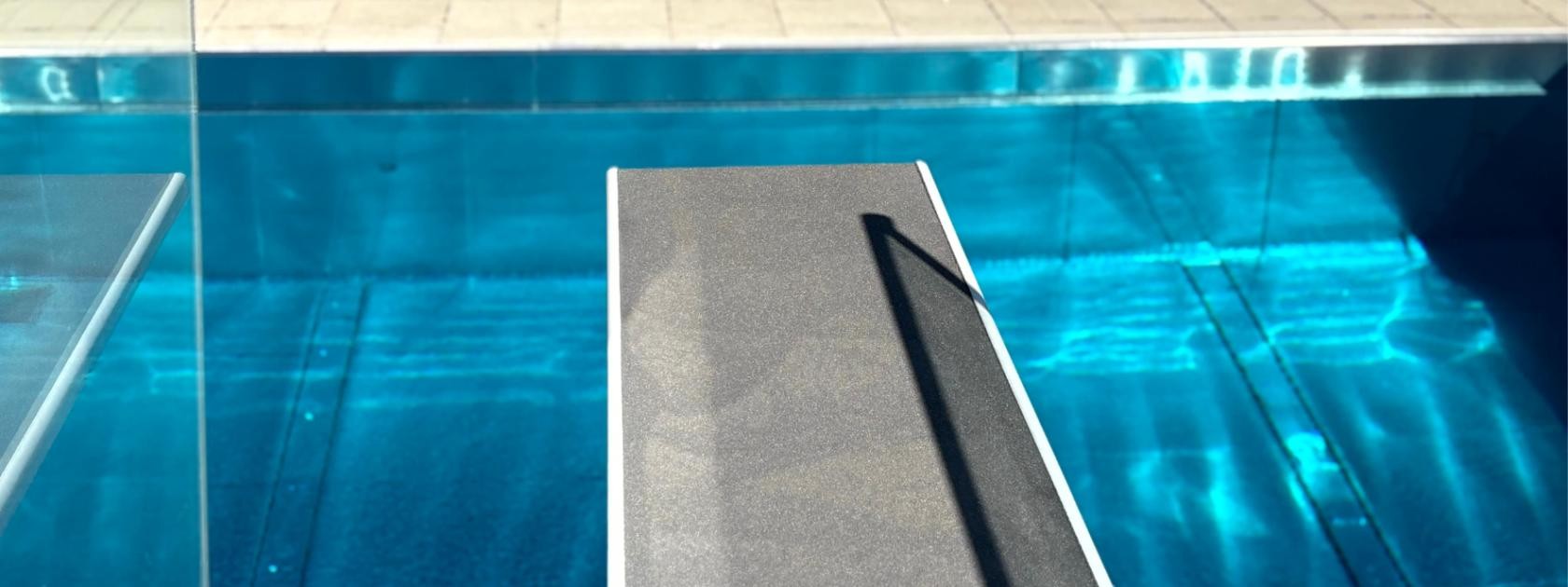 Bild vom Drei-Meter-Sprungbrett darunter glitzert das blaue Wasser.